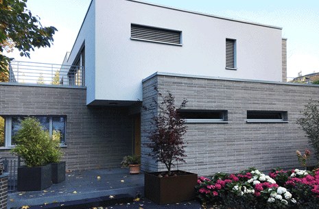 Modernes Wohnhaus mit weißem Obergeschoss und Klinkersockel auf einer Tiefgarage